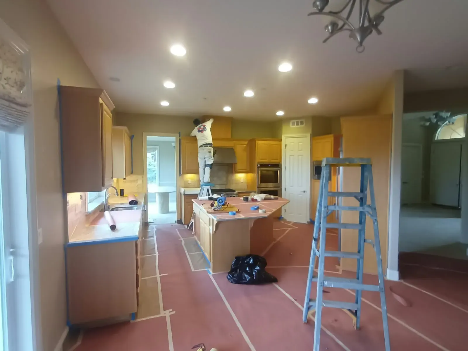 Interior painting in San Jose, CA: painter on a ladder with floors masked
