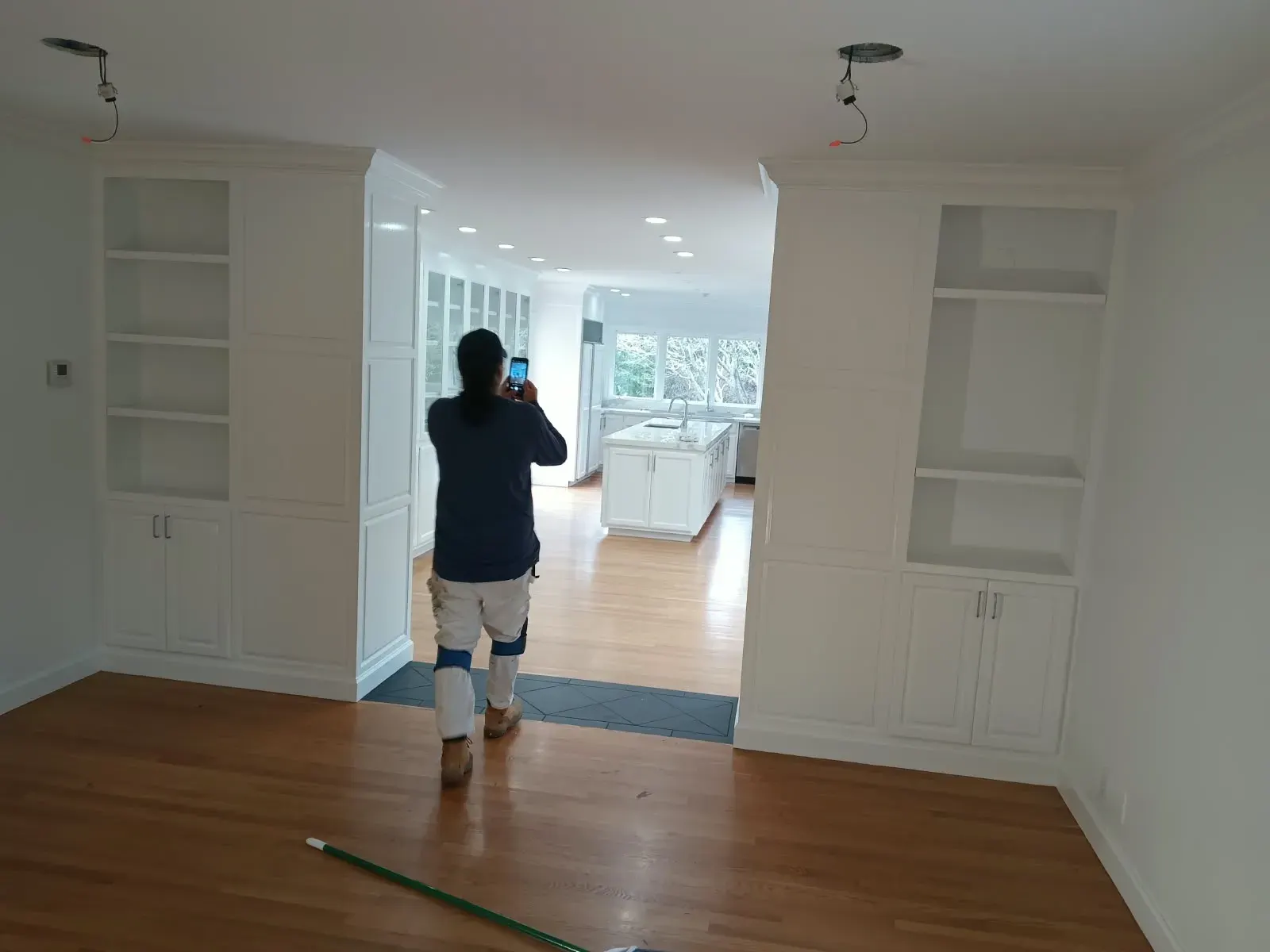 Painter walking through a freshly painted room with white built-in cabinets, De La Mora Painting, San Jose, CA