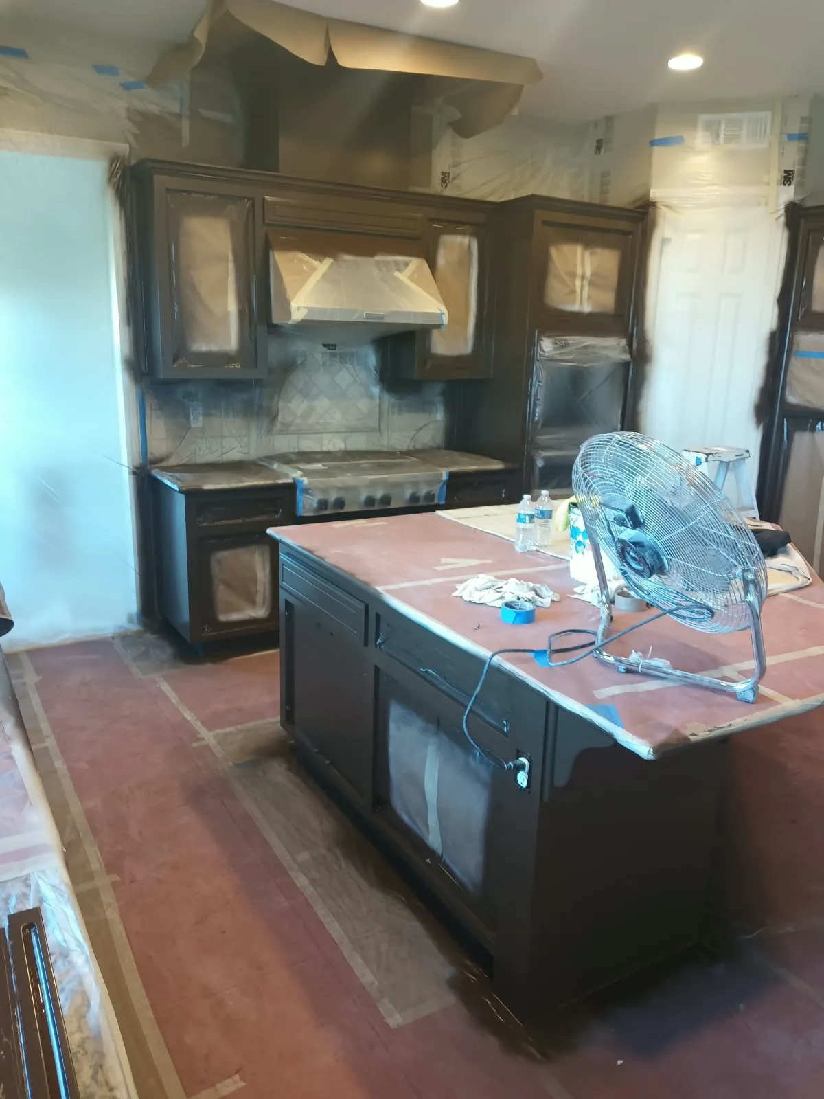Cabinet refinishing in San Jose, CA: dark kitchen cabinets masked with paper and plastic