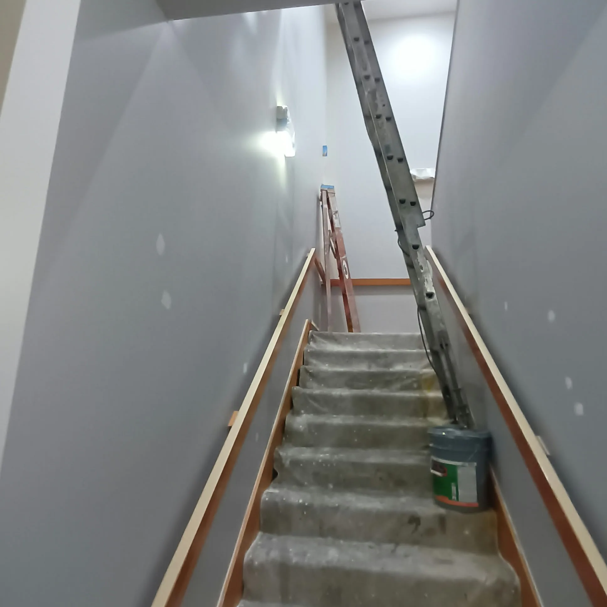 Staircase painting in San Jose, CA: stairwell with covered treads and ladder during painting